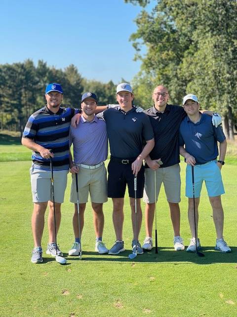 Five alums standing together on the golf course.